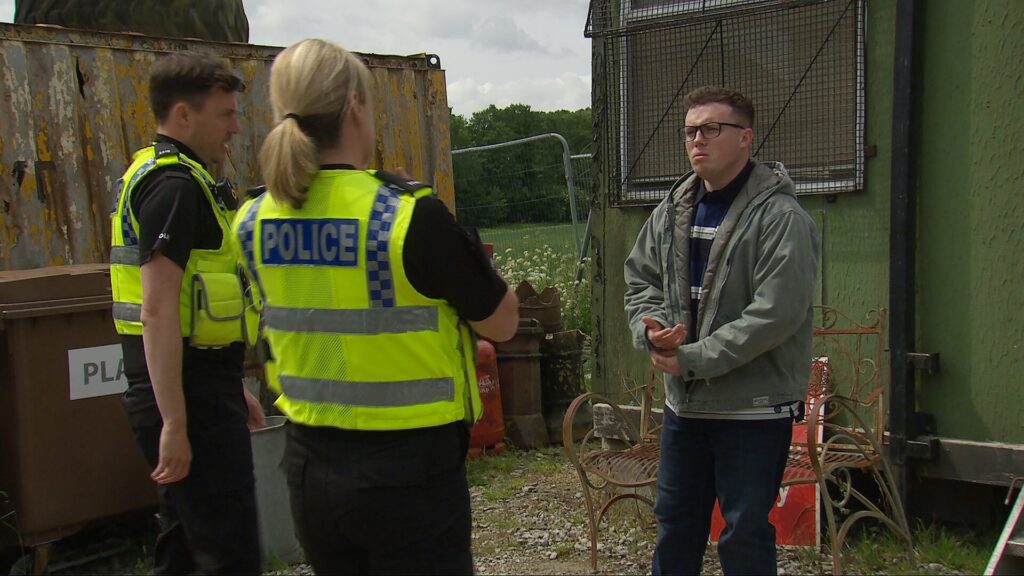 The police arrive at the scrapyard to speak to Vinny