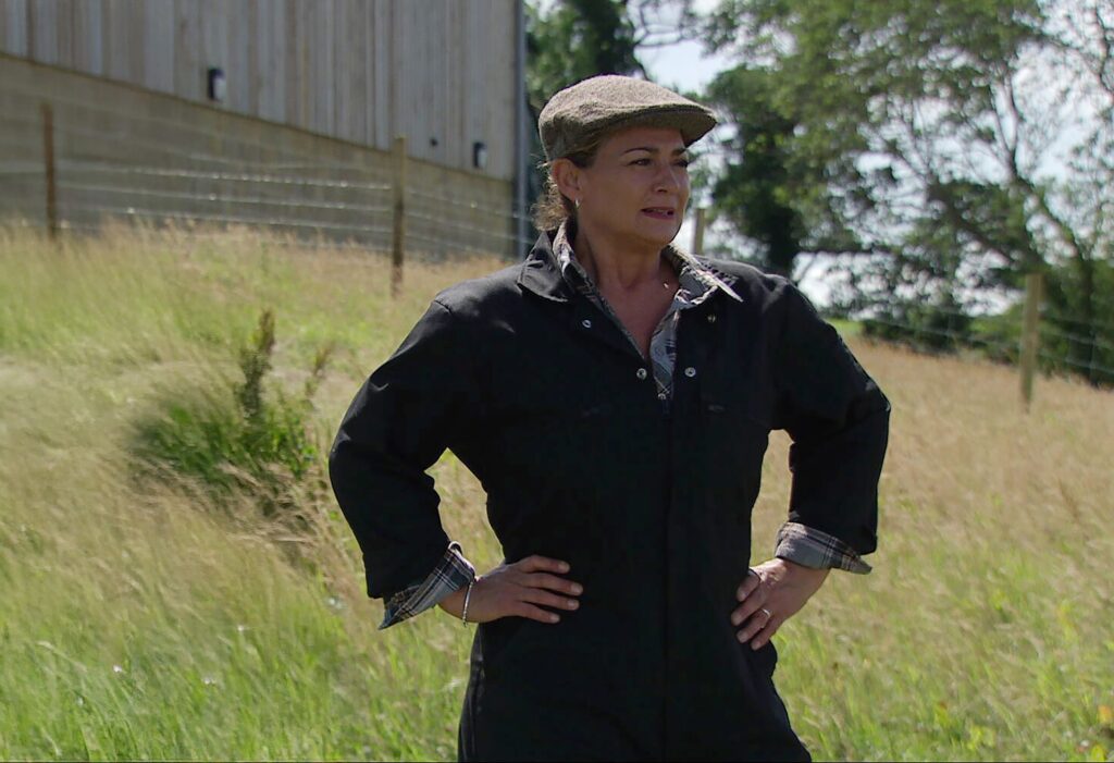 Moira stands looking over her land in Emmerdale