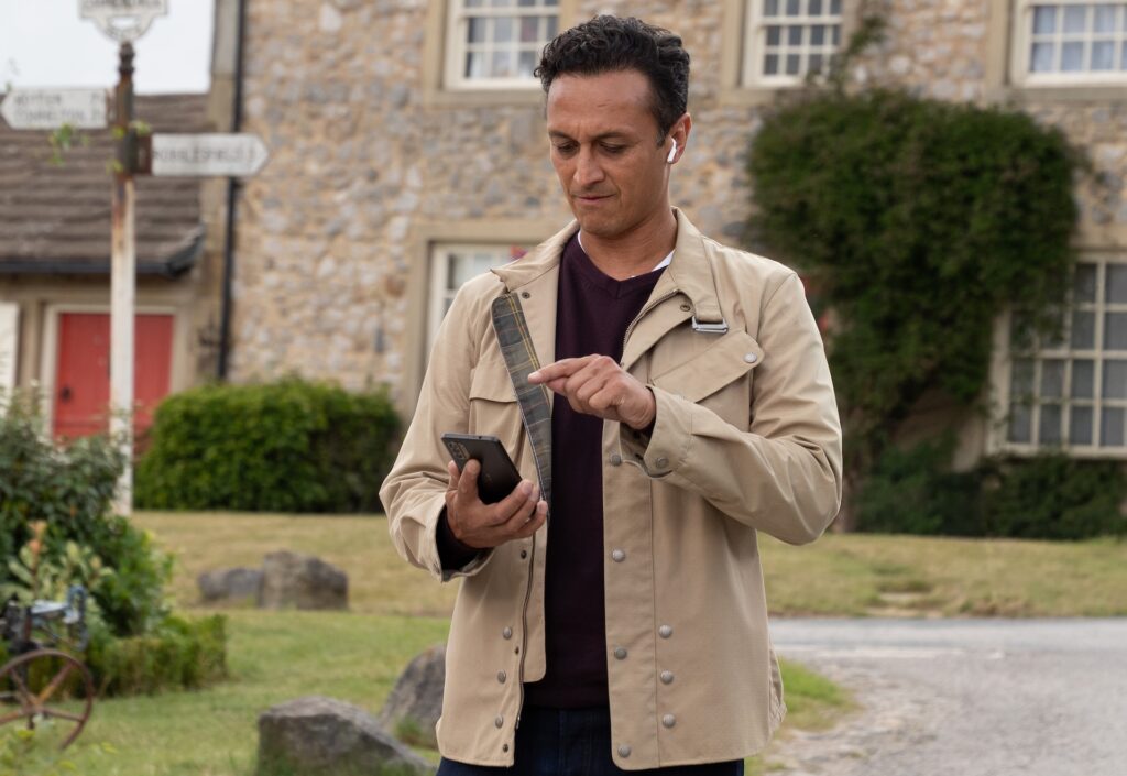 Jai looks at his phone in Emmerdale
