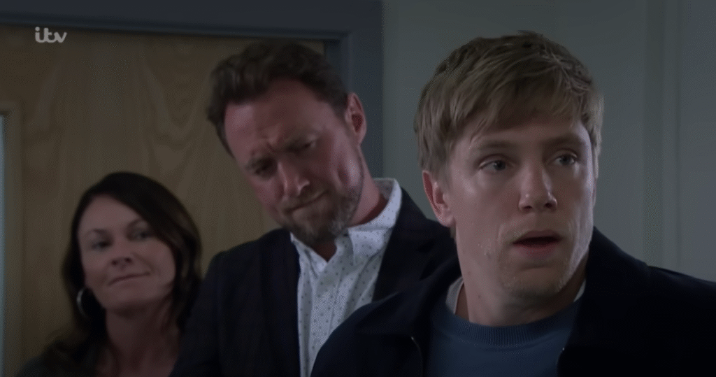 Chas smiling as Robert gets brought to the station