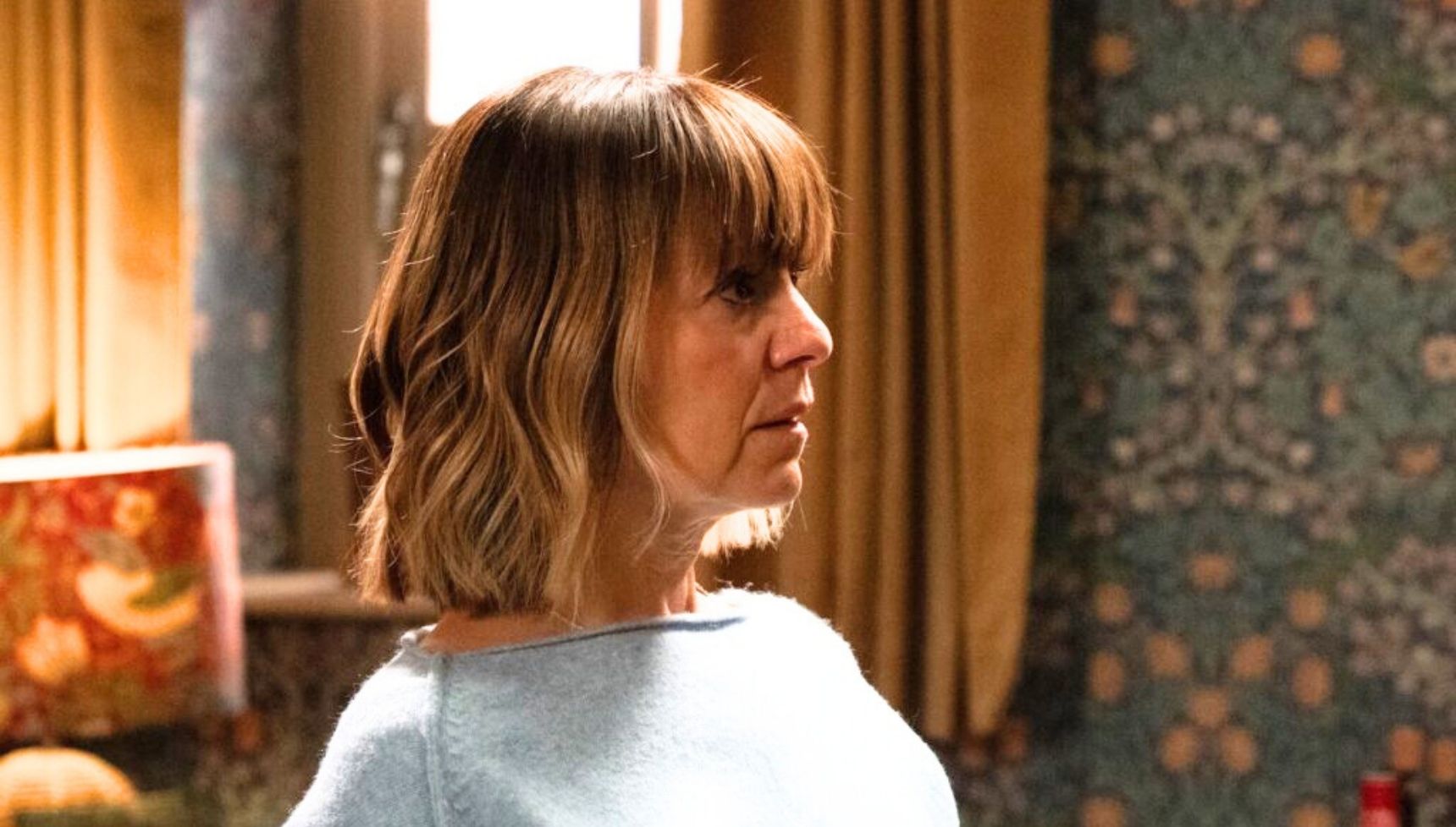 Rhona is in despair while a shadowy figure looms behind her